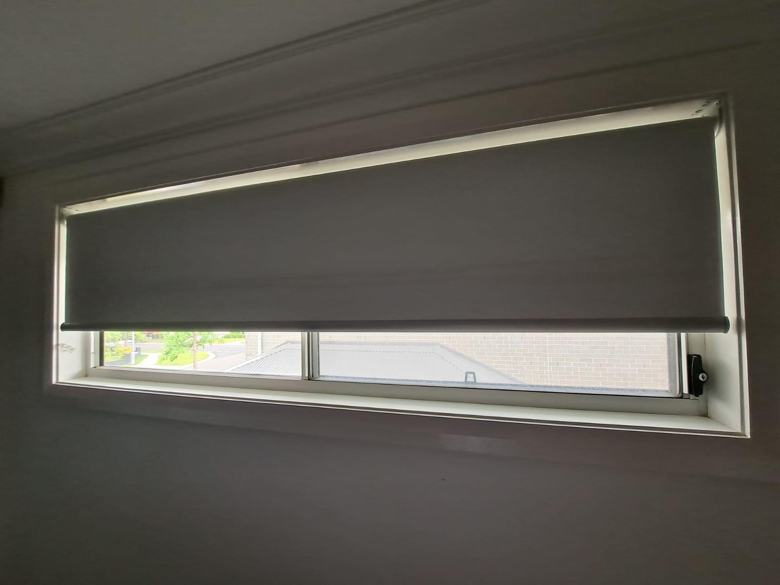 Slimline grey roller blind on a wide bedroom window